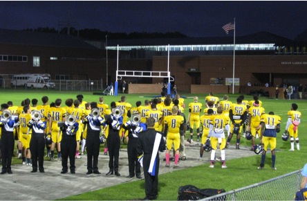 Each player of the football team stands facing the flag with their hands over their hearts during the National Anthem at the home game against Kellam on Oct. 9.