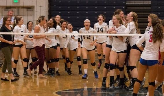 Girls’ volleyball team embracing after their win against Kellam on Oct. 18, in the gym.  Photo by Jim Hart.