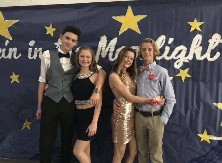 Freshmen (left to right) Zach Lund, Emma Miller, Julia Miller, and Alexander Brown pose in front of Homecoming banner at dance.