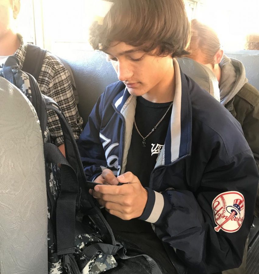 Sophomore Zachary Six checks Google Classroom on his cell phone on the bus ride home.
