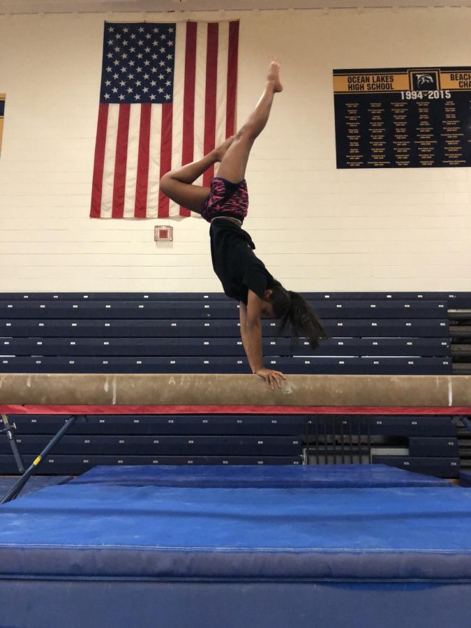 Senior Rutvi Patel performs a handstand on the balance beam in the Ocean Lakes gymnasium on Nov. 30, 2017.