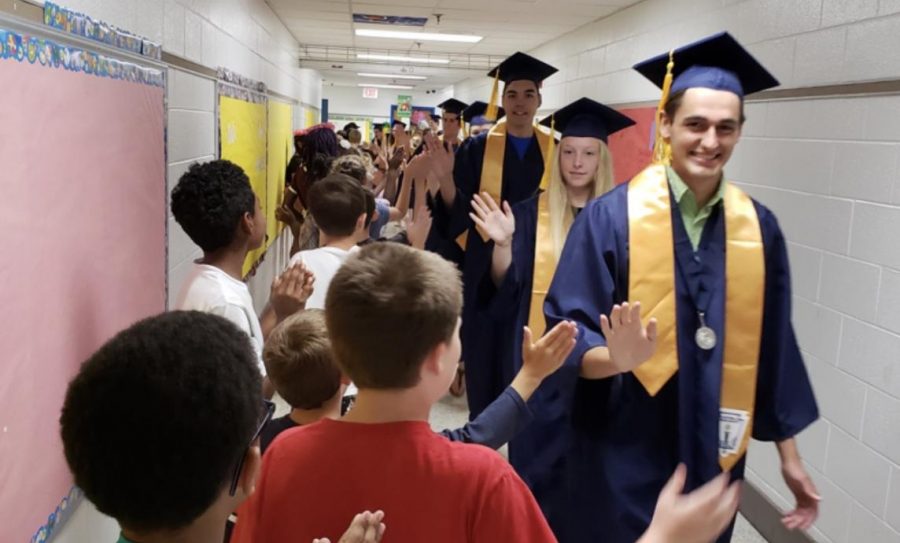 Seniors walk down hallway to high five the elementary students at Ocean Lakes Elementary. 