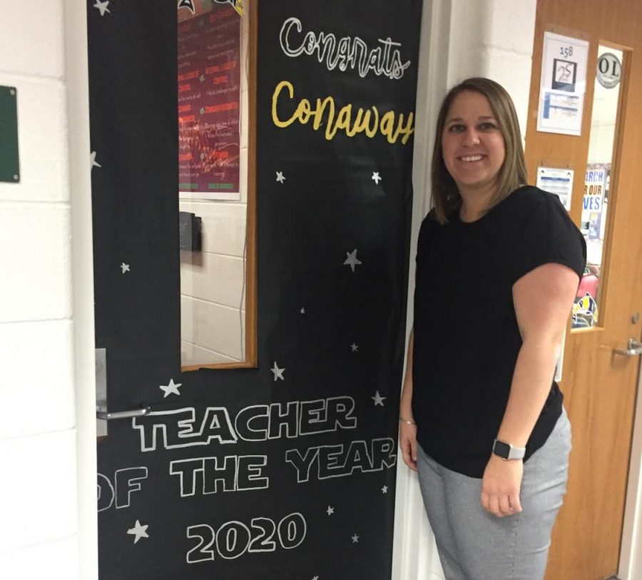 Teacher of the Year, Carlin Conaway, poses in front of her classroom door designed by SCA.