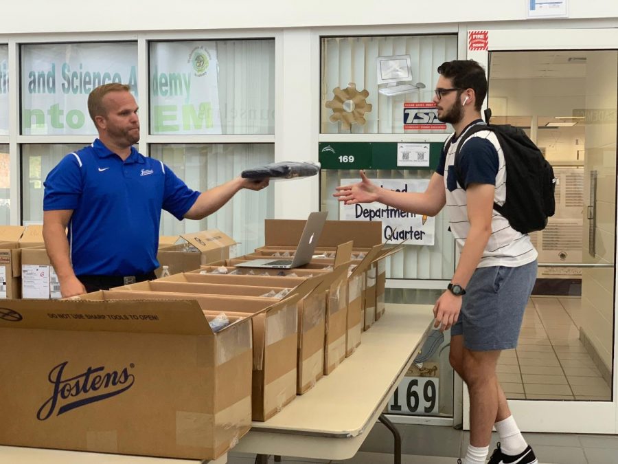 Senior Ryan Marerro collects his cap and gown package from a Jostens member in the gym foyer on April 8, 2019. 