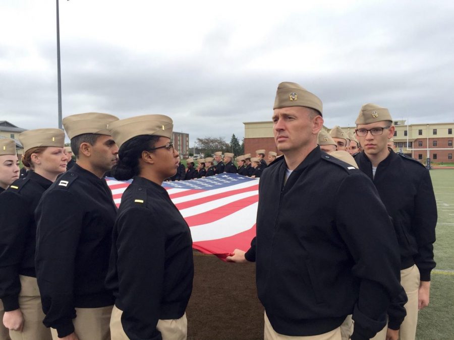 Chaplain Jeff Owens stands at attention next to the American flag.