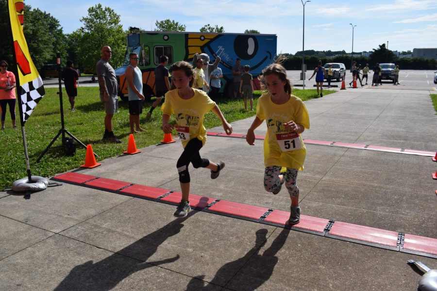 English teacher Jessica Scheibles twin daughters, Lucy and Brianna, cross the finish line and head to gym for after race festivities. 