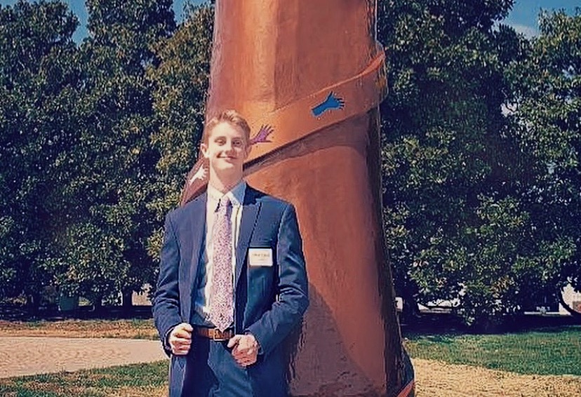 Junior Pierce Corson stands proudly in front of hand sculpture.