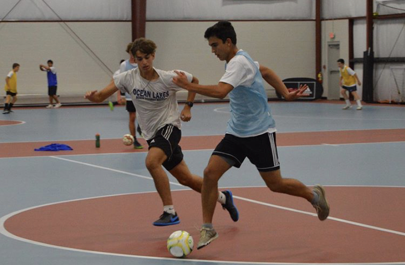 Seniors Matthew Escobar and Jacey McFaddin fight for the ball at the Beach FC indoor facility on Oct. 17.