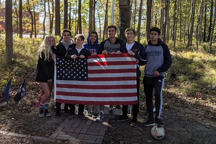 From left: Meredith King, Troy Daigneau, Anthony Crispin, Dakota Gordon, Matt Escobar, Alex Cigurov,  and Yusuf Cetin hold an American flag on the trail on Nov. 11.