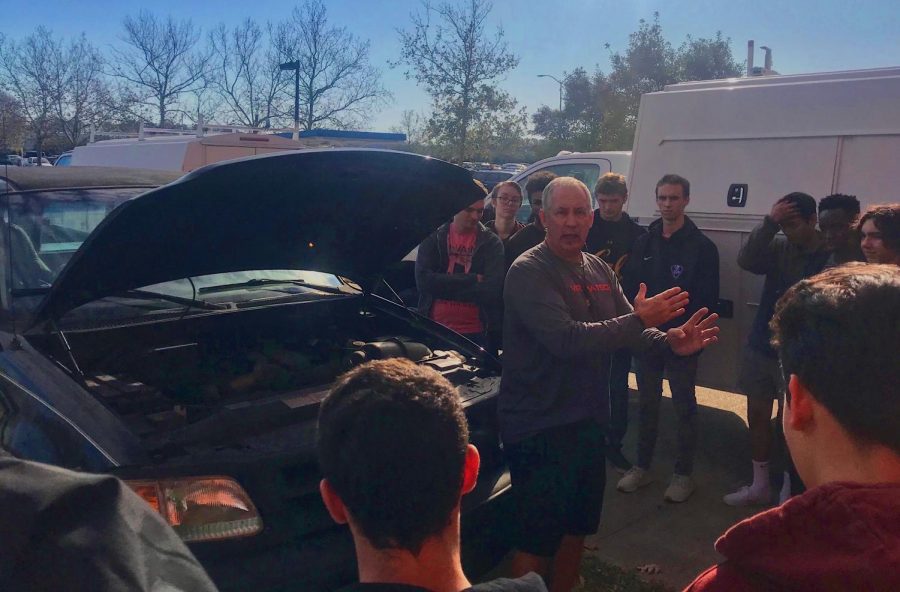 Students learn how to change a tire and jumpstart a car with health and PE teacher Pete Zell during their advisory block outside on Dec. 4. 