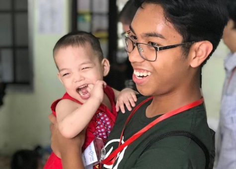 Jondre Macaraeg smiles with a baby at an orphanage during an Operation Smile trip to Vietnam in 2019.