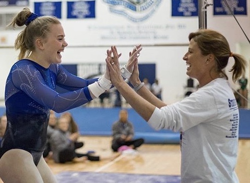 Sam Lee, sophomore, celebrates with coach Jennifer Ramey after a successful gymnastics meet.