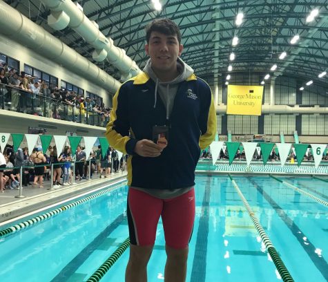 Kendall stands on the blocks at George Mason Aquatic Center with his second place state medal at the conclusion of the meet. Feb. 22. 