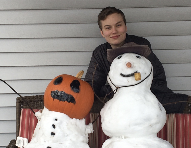 Even though students did not get a day off from virtual school, junior Tim Doughty poses with snowmen he built during lunch. Pumpkin head snowman was designed to look like a Minecraft snow golem.  