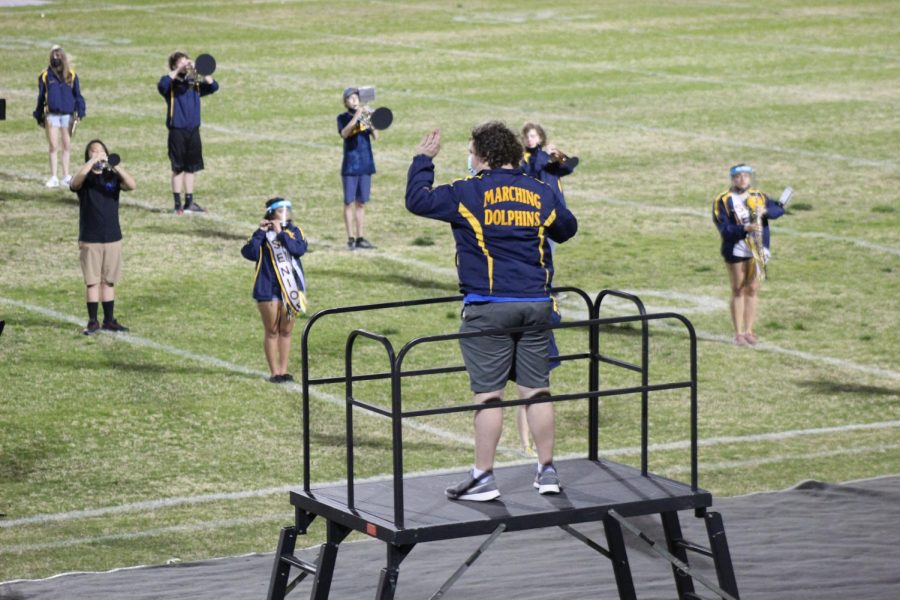 Senior Matthew Pohl leads the marching band during their performance at the senior night football game on March 26.