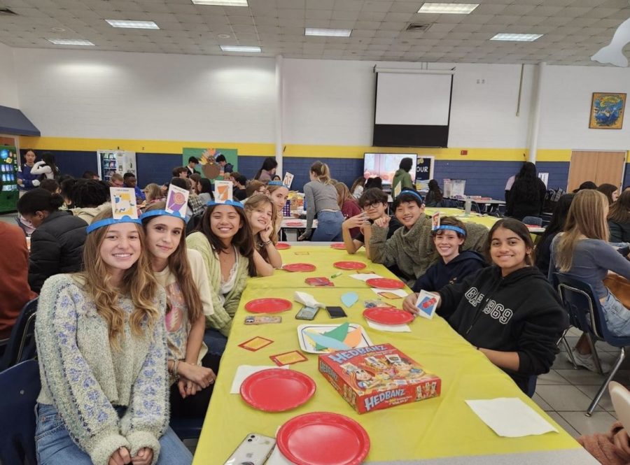 Freshmen Maddie Murrell, Aubrey Spagnoli, Carmela Mendoza, Reese Longwater, Ethan Royce, Daxing Yang, Miles Pullman and Anisha Warusavitharana (from left to right) smile for a photo while playing Hedbanz during Finsgiving Celebration Nov. 18, 2022.