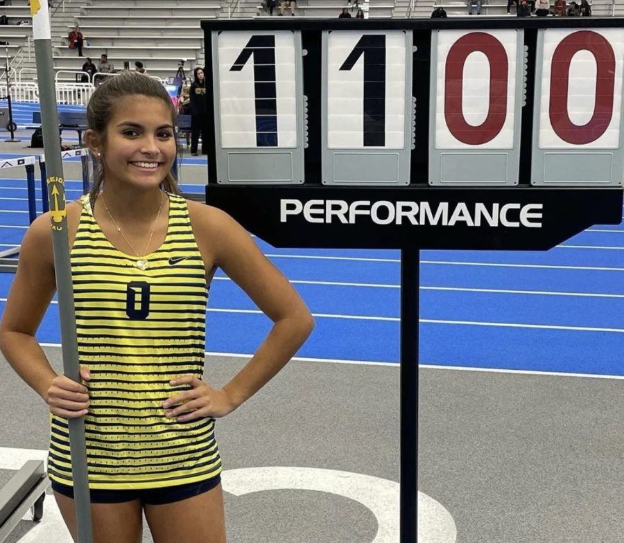 Pole vault state champion, Brooke Gunter, poses in front of her new personal record and school record at the first indoor track meet of the season at the Virginia Beach Sports Center on Wednesday, Dec. 14, 2022.
