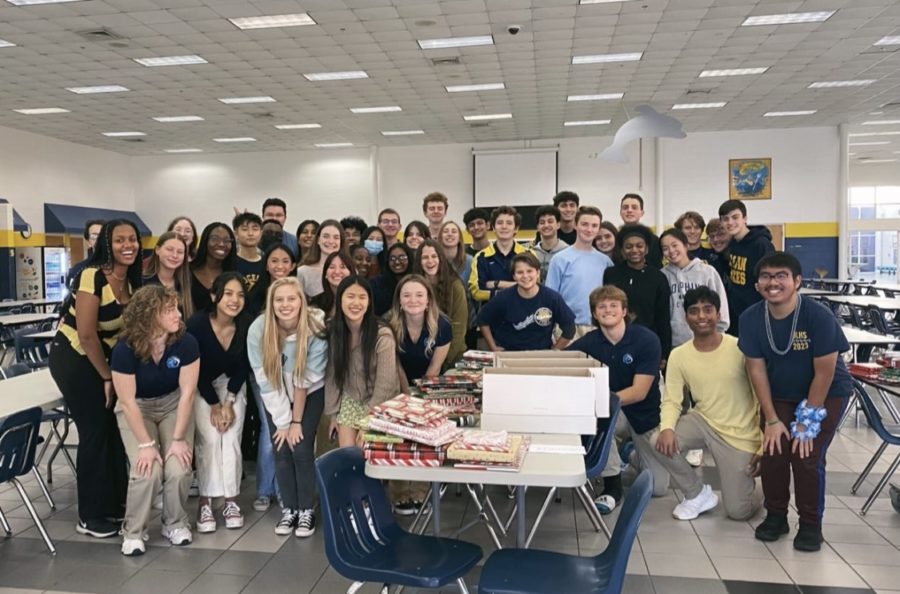 National Honor Society students celebrate by the 239 books they wrapped for Birdneck Elementary School for their winter service project on Dec. 16, 2022 in the cafeteria. 