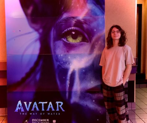 Senior Abby Martin inside Regal Theaters with an advertisement about the new movie, “Avatar: Way of the Water.”
