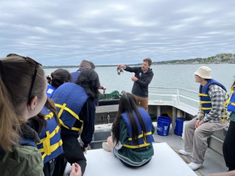 The Biology Club watches Rick Mittler, the Brock Centers Virginia Student Leadership Coordinator, as he holds up a crab on the Chesapeake Bay on April 24, 2023.