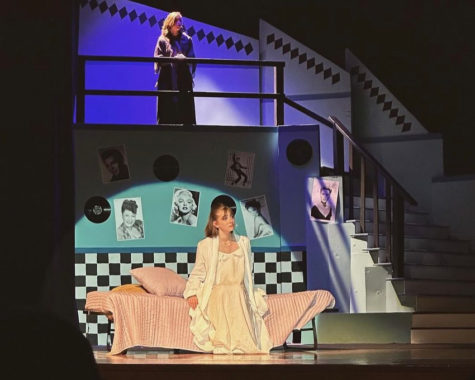Junior Victoria Maldonado glances over the balcony as the spotlight shines below on freshman Anneliese Wedertz who is about to begin her debut on May 6, 2023 at the Grease production.