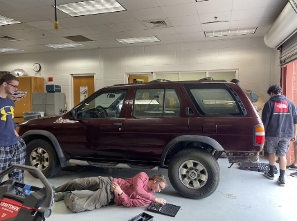 Students Devin Santiago, Jackson John and Trey Levrett work on the Nissan Pathfinder in room 164 on May 16, 2023.