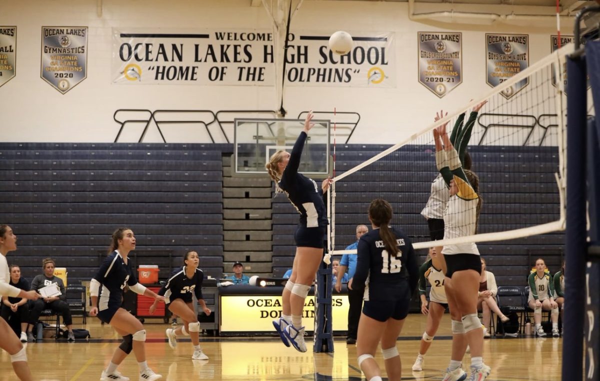 Senior Olivia Box attempts to swing around the block to earn a kill for her team against Cox on Sept. 7, 2023 at Ocean Lakes High School. 