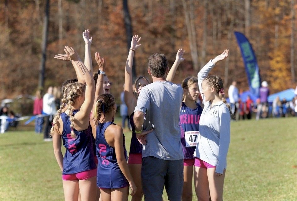 The Ocean Lakes girls cross country team huddles together prior to the VHSL 5A State Championship race on Nov. 11, 2023, at the Oatlands Plantation course in Leesburg, Va. Photo used with permission from Mary Ann Magnant.