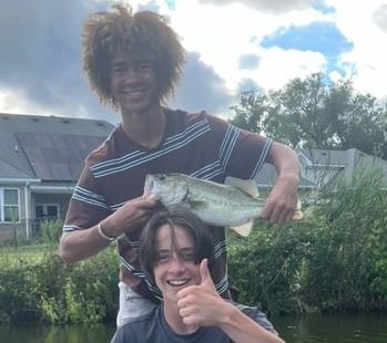 Aboubakr Sissoko (top) and Caleb Tomberlin (bottom) show off a freshly caught largemouth bass at Lagomar Lake on July 16, 2023.