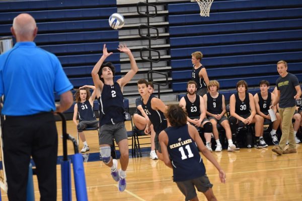 (from left) Donny Velazquez sets the ball with his teammates, Nathan Brock and Michael Domanski, preparing for a spike and the rest of the team looking on from the sidelines during a match against Landstown High School on Aug. 28, 2023.  Photo used with permission from Diana Holloway.