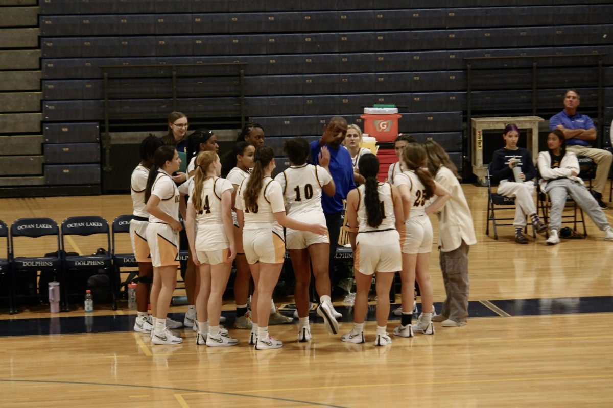 Lady Dolphins huddle in front of the bench during halftime to discuss what plays they will change as they take on the Salem Sundevils at Ocean Lakes on Nov. 30, 2023.