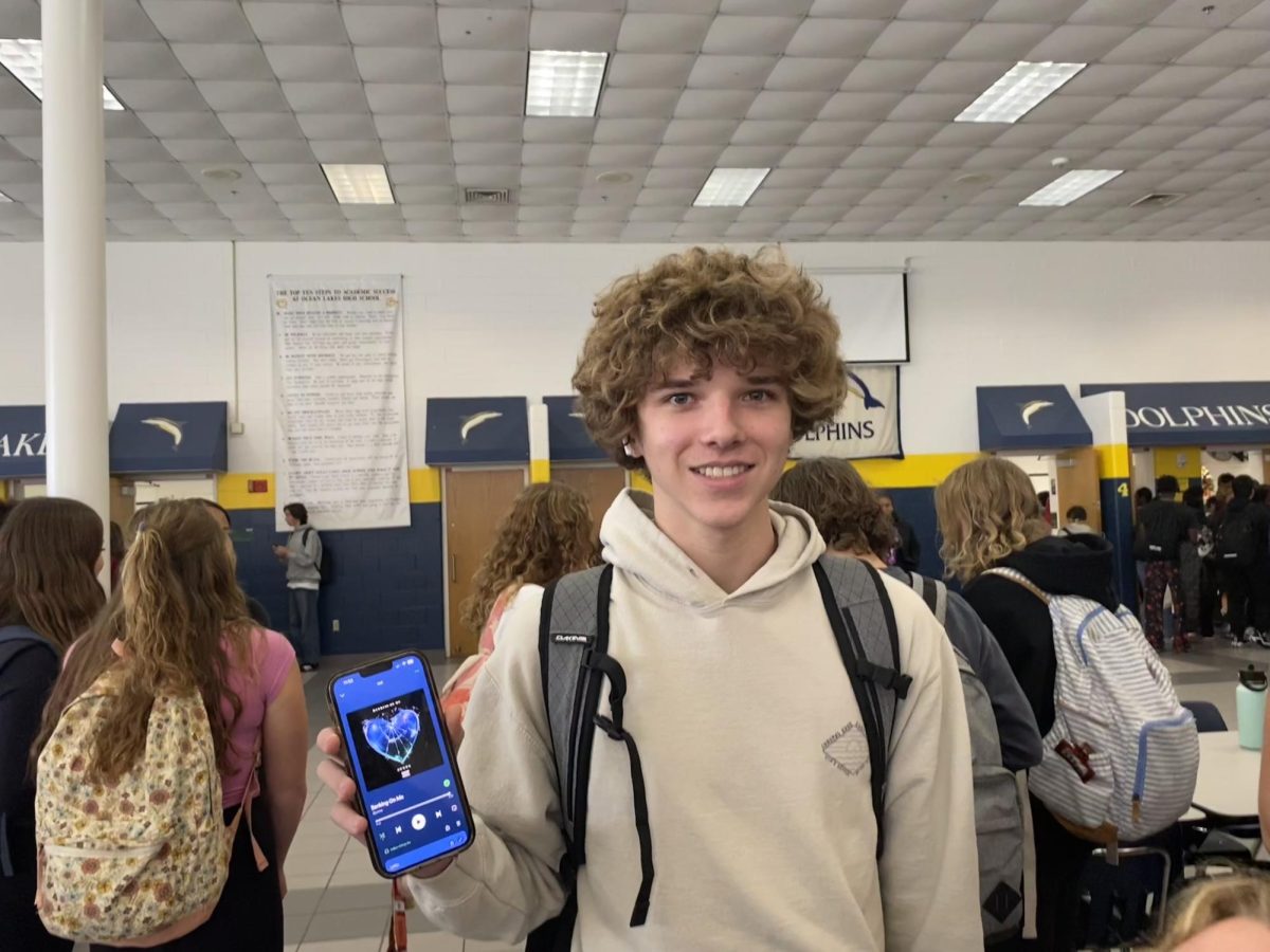 Sophomore+Colby+Wadington+holds+up+his+phone+to+show+the+music+he%E2%80%99s+listening+to+in+the+cafeteria+on+December+11%2C+2023.+