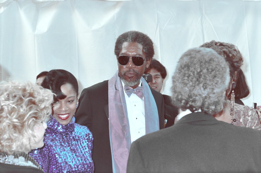Morgan Freeman sports some cool shades and a fashionable bow tie at the 1990 Academy Awards. Throughout his lengthy and influential career, Freeman has garnered numerous awards and established himself as one of the most successful in the film industry. (Morgan Freeman and his wife, Myrna Colley-Lee/Alan Light/Flickr/CC BY 2.0 DEED)