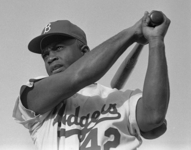Baseball player Jackie Robins looks on as the ball takes flight during a game in 1954. (Jackie Robinson/Bob Sandberg/WikimediaCommons/CC-BY-SA-2.0)