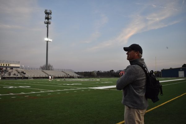 Head athletic trainer David Lehan stands on the sideline on March 14, 2024, during the boys soccer game against Grassfield at Ocean Lakes High School.