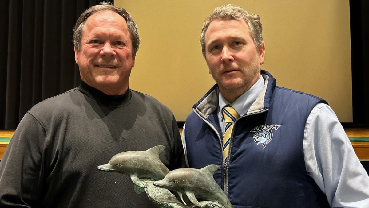 Former football coach Jim Prince passes on his dolphin statue to MSA coordinator Michael King in the auditorium on Feb. 26, 2024.