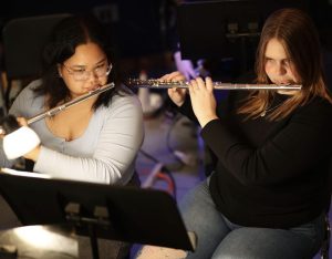 (from left) Junior Janna Maninang and freshman Karley Farrar both play the flute for the pit orchestra during the Ocean Lakes rendition of The Sound of Music on April 24, 2024. The addition of the full pit orchestra for the entirety of the musical has helped set Ocean Lakes theater performances apart. Photo used with permission from Jared Swift.