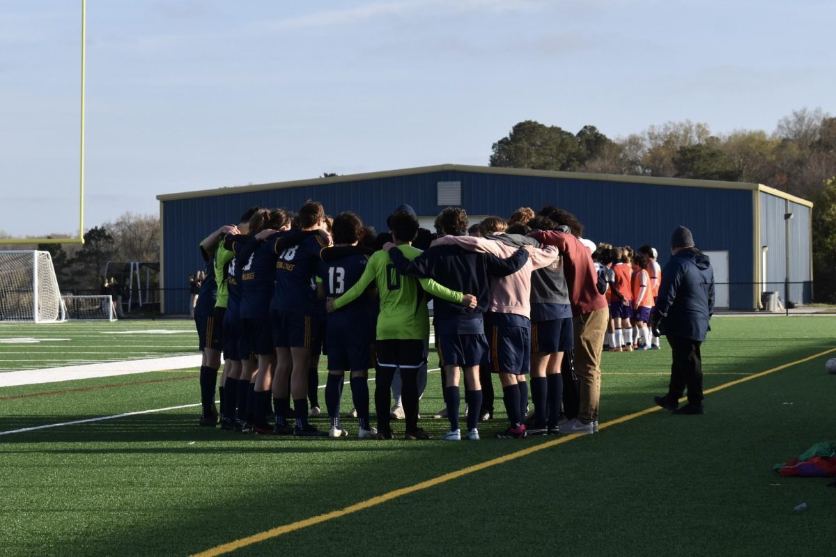 The+boys+varsity+soccer+team+gather+in+a+huddle+moments+before+they+faced+Deep+Creek+High+School+at+Ocean+Lakes+High+School+on+March+25%2C+2024.+Ocean+lakes+won+the+game+after+defeating+Deep+Creek+with+a+score+of+7-1.