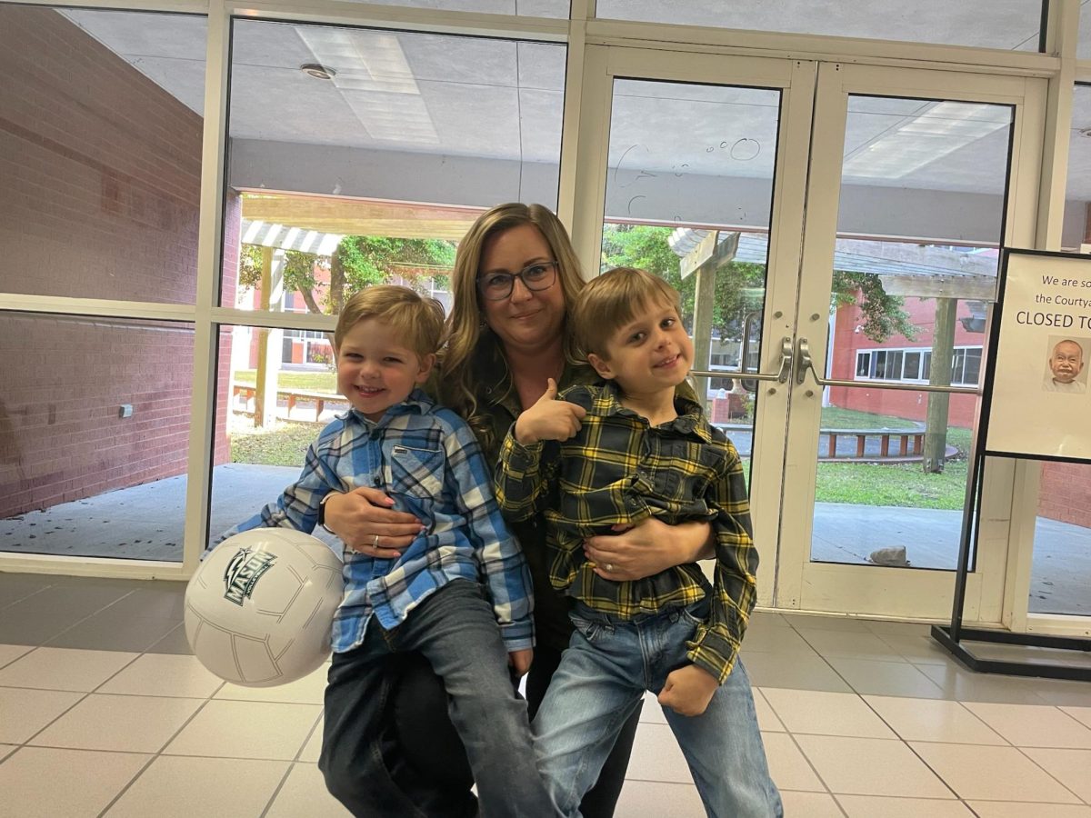 Personal finance and digital applications teacher Christina Barnhart holds her two sons outside the courtyard entrance on Bring Your Kid To Work Day on April 25, 2024.
