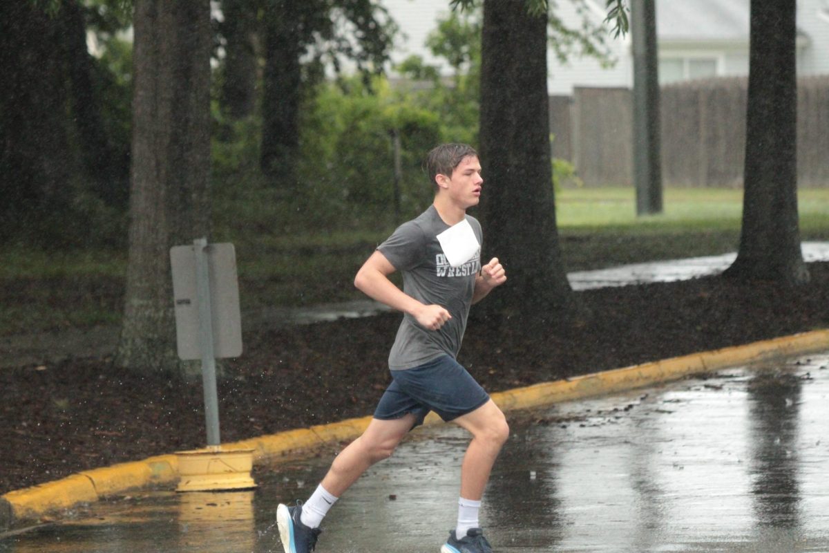 Junior Paul Chapman dashes through the rain at the Dolphin Dash 5k on May 18, 2024, in front of Ocean Lakes High School. Paul placed first in the junior division and is a member of the wrestling team. Photo used with permission from Henry Yu. 
