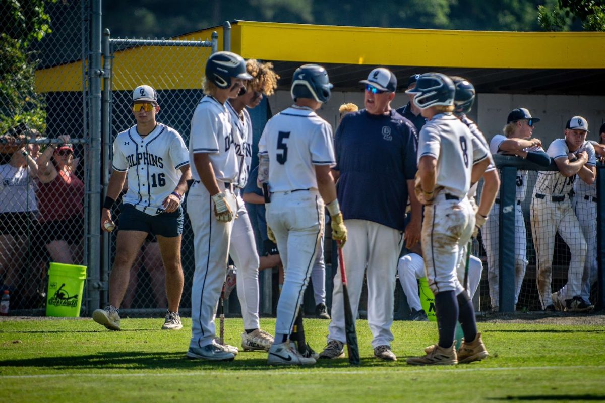 Varsity+baseball+offense+meets+with+head+coach+Peter+Zell+to+discuss+a+mid-game+debrief+on+June.+4%2C+2024%2C+at+Ocean+Lakes+high+school+for+5A+State+Quarter-Finals+against+Maury+High+School.+Photo+used+with+the+permission+of+Melanie+Meneses.+