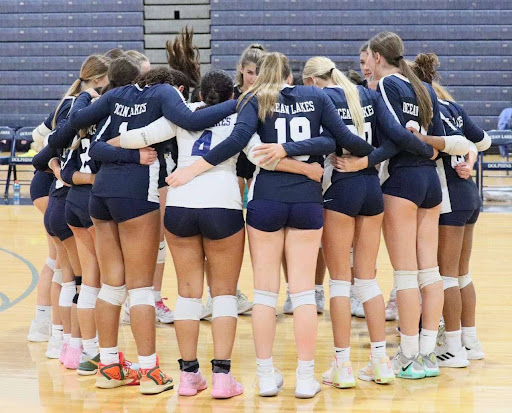 Girls volleyball huddles together before their game against Grassfield High School on Aug. 27, 2024, at Ocean Lakes High School. The Dolphins took the win with a final score of 3-0. Photo used with permission from Kennedy Walls.