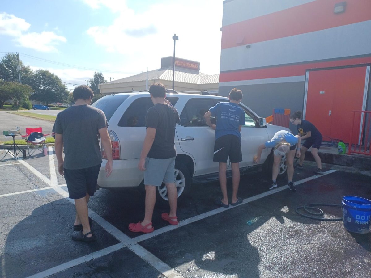 From left to right, sophomore Frankie Graninger, sophomore Cole Graninger, sophomore Andrew Koivu, junior Grace Kavanaugh and sophomore Esther Gammill wash a car on Virginia Beach Blvd on Sat., Sept. 21, 2024.