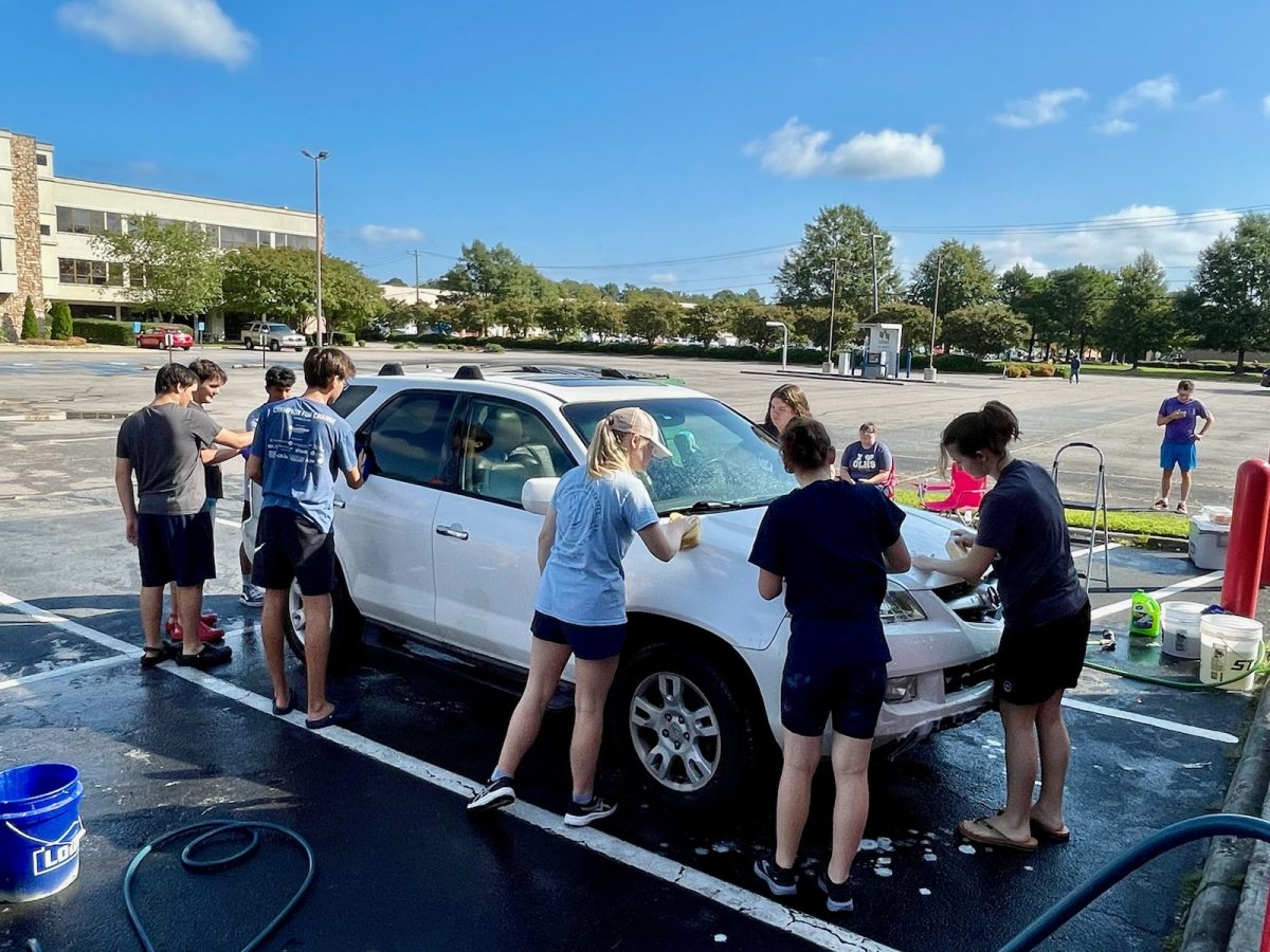 From the back of the car to the right and around, sophomore Chris Litto, sophomore Frankie Graninger, sophomore Cole Graninger, sophomore Andrew Koivu, junior Grace Kavanaugh, sophomore Esther Gammill, freshman Vivian Wallace and freshman Poppy Purton wash a car on Virginia Beach Blvd on Sat., Sept. 21, 2024.