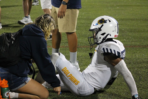 Senior athletic trainer Jade McAboy helps senior Devin McGill treat a cramp on the sideline at Kellam High School on Sept. 20, 2024. The Dolphins took the win with a final score of 21-3.
