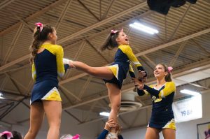 Junior Carly Brand performs an arabesque in the pyramid, while being held by senior Lily Lipsky and junior Mckinzy Hill at the beach districts competition on Oct. 9, 2024. They will compete again on Oct. 26, 2024, at Green Run High School. Photo used with permission from Ted Calise. 
