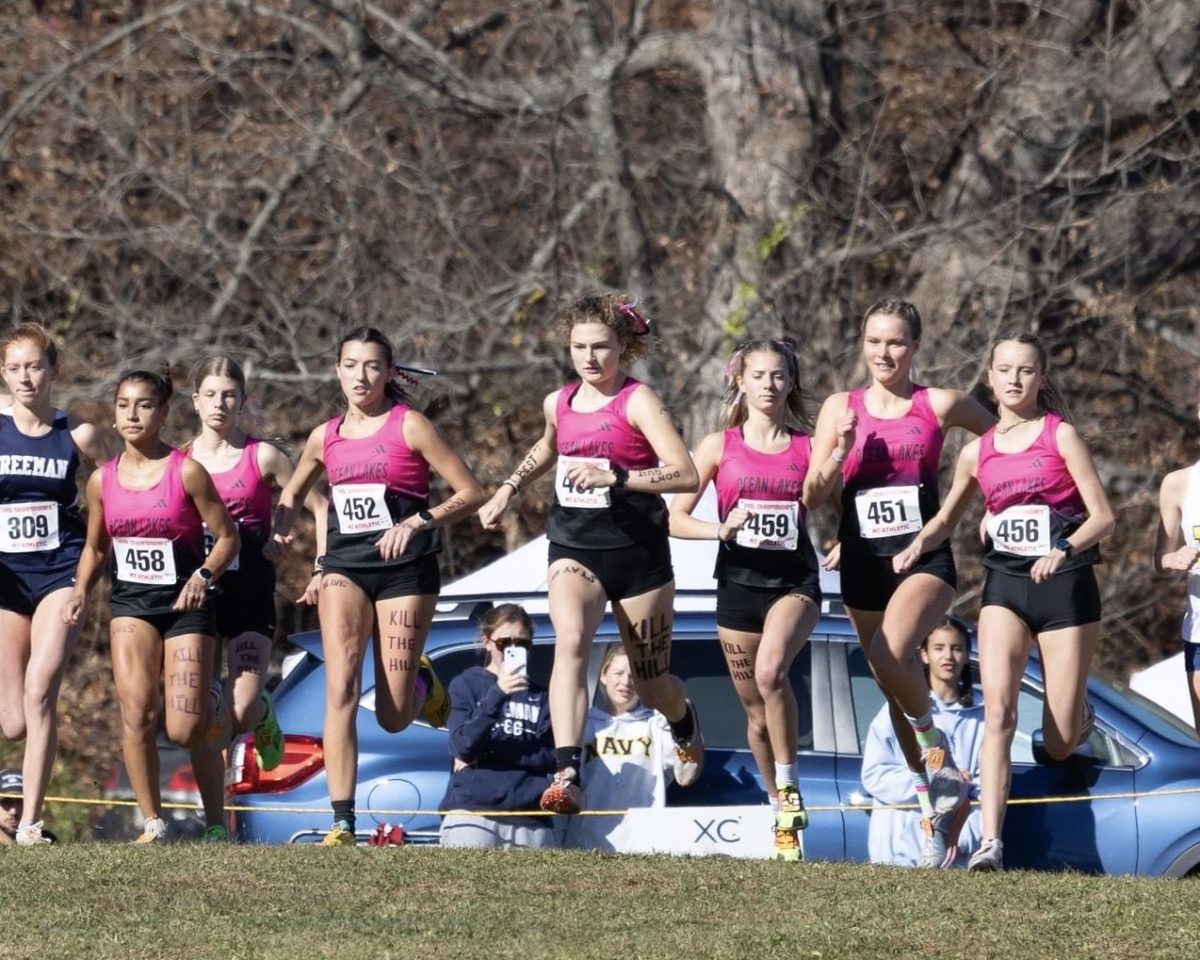 From left: senior Khadija Sissoko, sophomore Eva Wagnen, seniors Riley Gomez, Lauren Rakov, Grace Thompson, junior Frederika Bartsch and senior Lindsay Meadows begin racing at the VHSL Class 5 State Championship race at Oatlands Plantation in Leesburg, Va. on Nov. 16, 2024. In honor of the challenging hills at Oatlands, the girls wrote “Kill the Hill” on their legs. Photo used with permission from Christine Rakov.