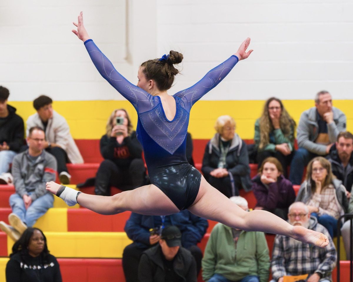 Senior Katie Wilkinson executes a switch half during her floor routine at their competition against Bayside and Landstown High School. The meet was hosted by Bayside High School on Dec. 5, 2024. Photo used with permission by Ted Calise.