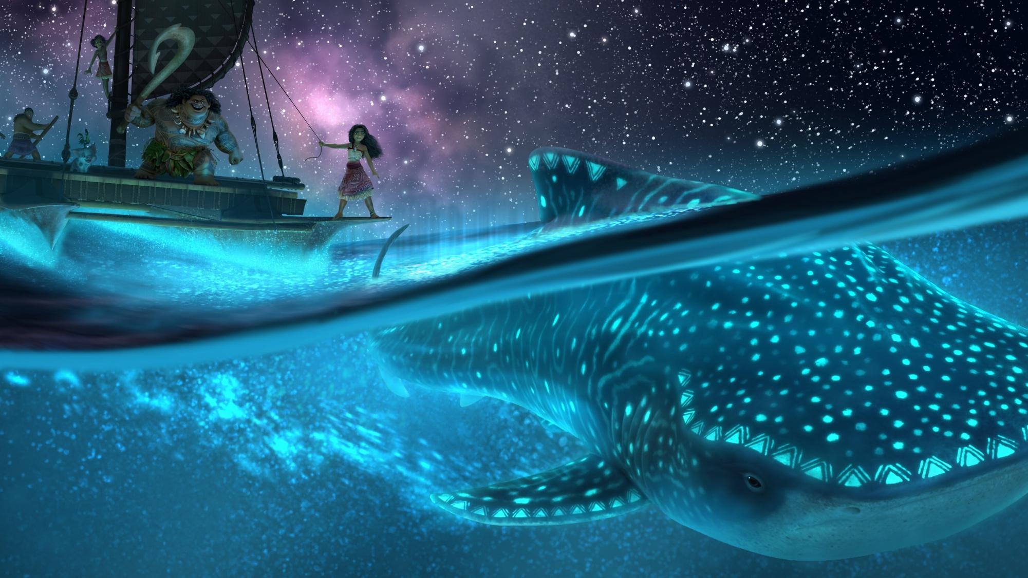The image shows a lit-up blue whale gliding underneath Moana’s boat as she looks out into the horizon. Image courtesy of Disney UK.