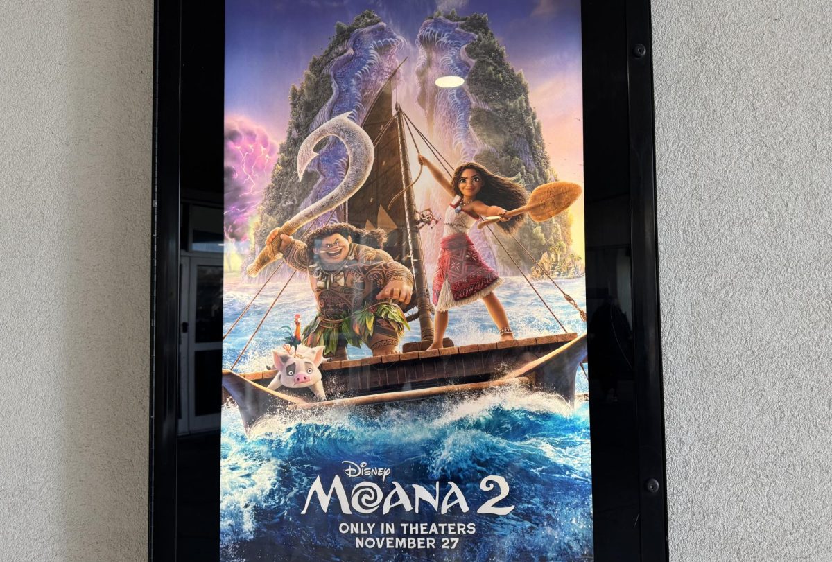 The “Moana 2” movie poster graces the wall of the AMC at Lynnhaven Mall on Dec. 24, 2024. It depicts Moana, now three years older, with Pua in the foreground and Maui in the background.